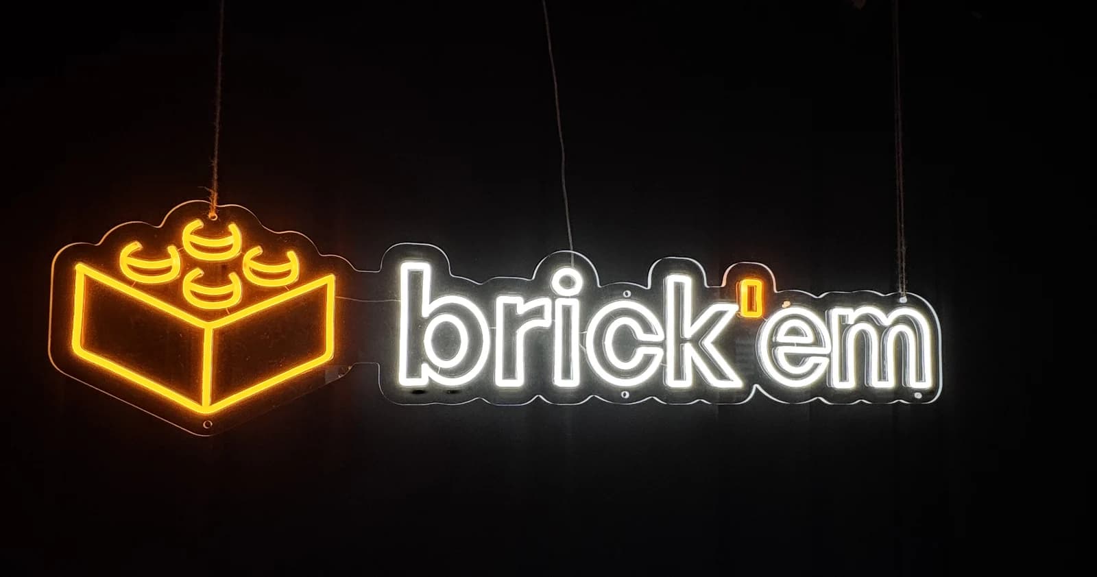 The brick'em neon sign, an orange brick and white wordmark, hanging in the office